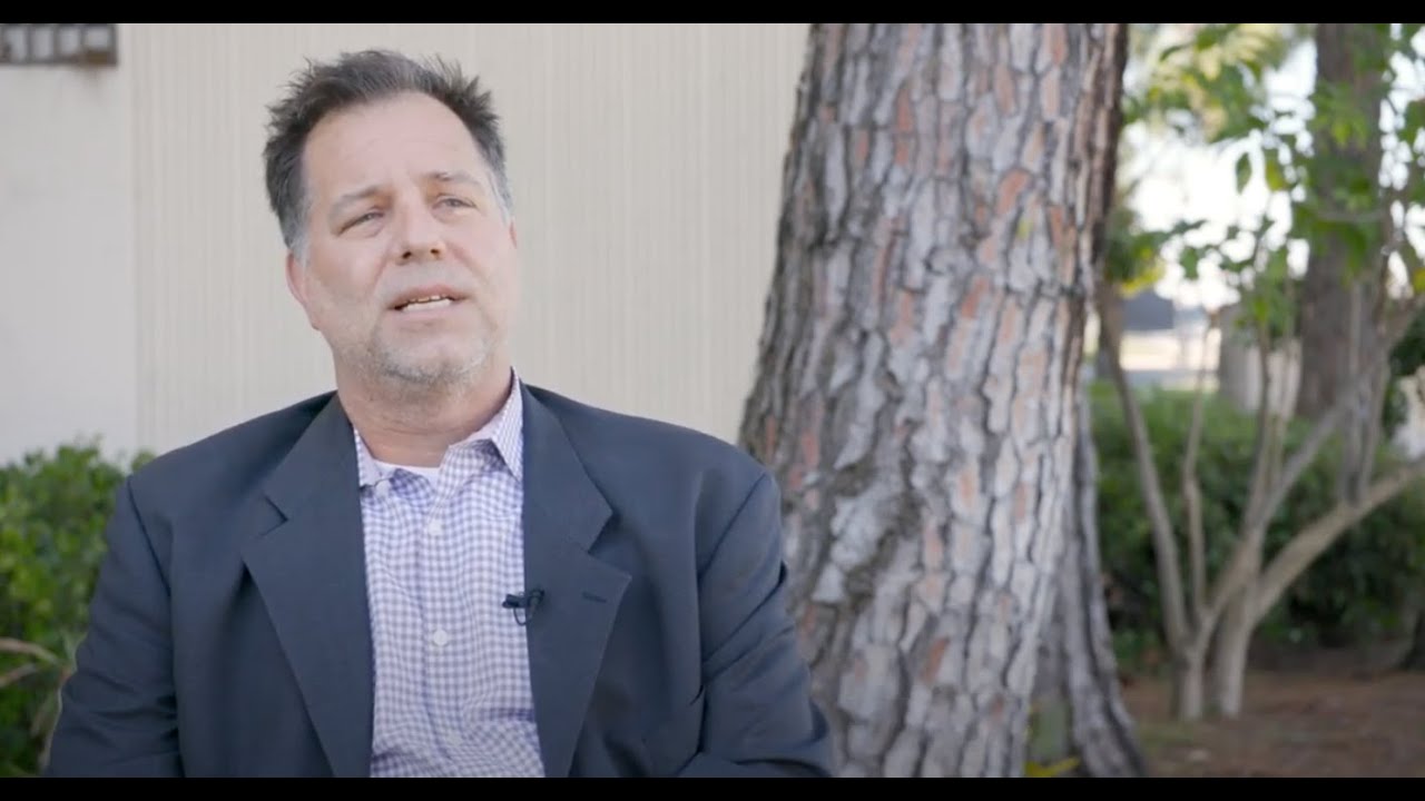 Mark Reed talking in front of a tree