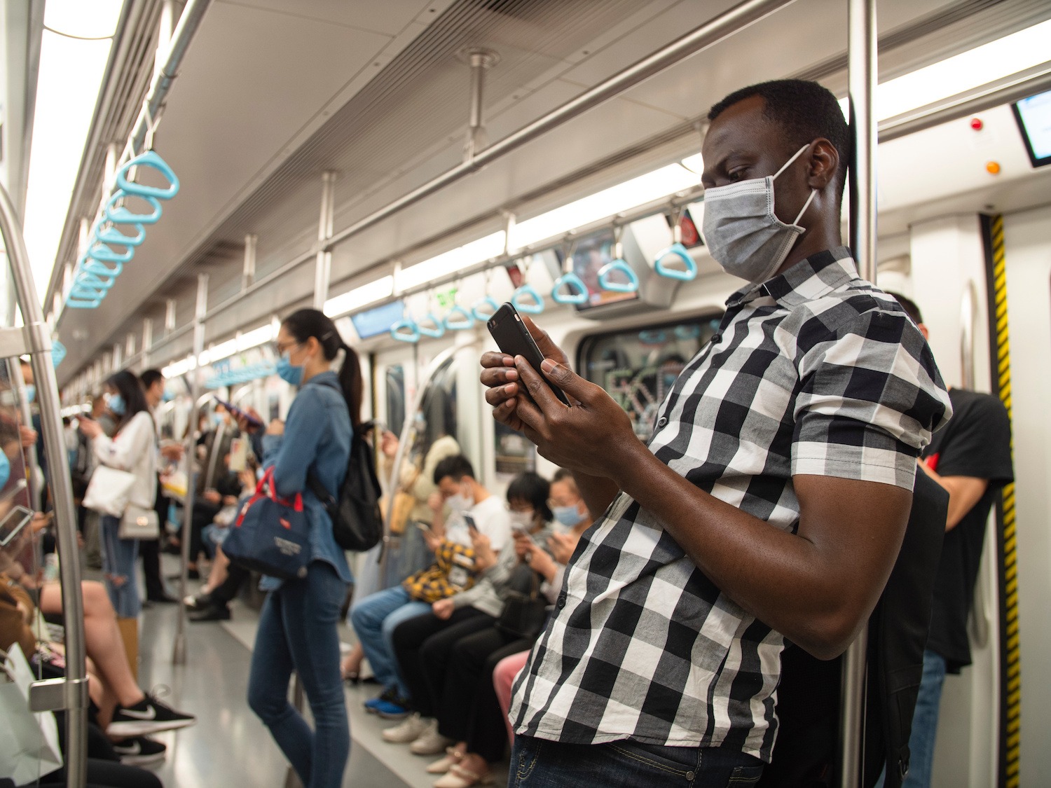 man wearing mask in the subway using mobile phone