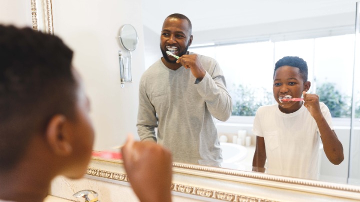 father and son brushing teeth together