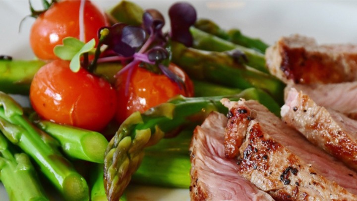 plate of food with tomato, asparagus, and red meat