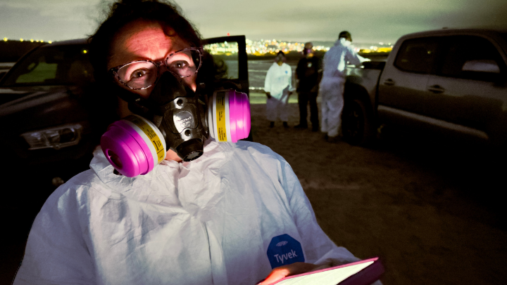 Paula Stigler Granados measures H2S gas levels at Tijuana River with gas mask and white medical suit
