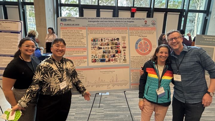 Three students and one Professor posing in front of a research poster